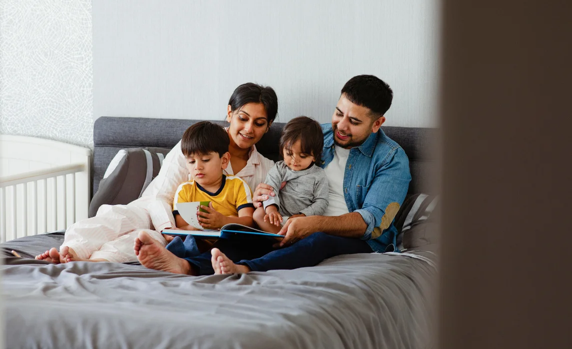parents teaching their kids to read in the bedroom