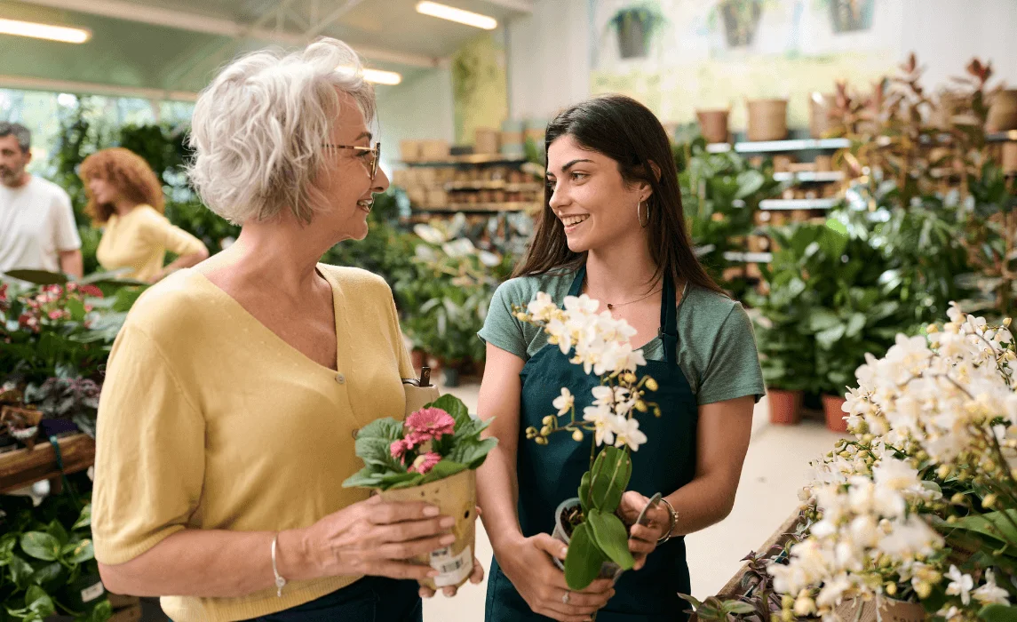 two people talking while holding plants