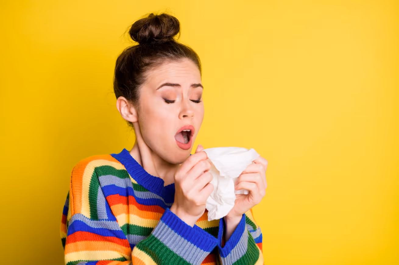 Woman sneezing into a tissue due to allergy symptoms