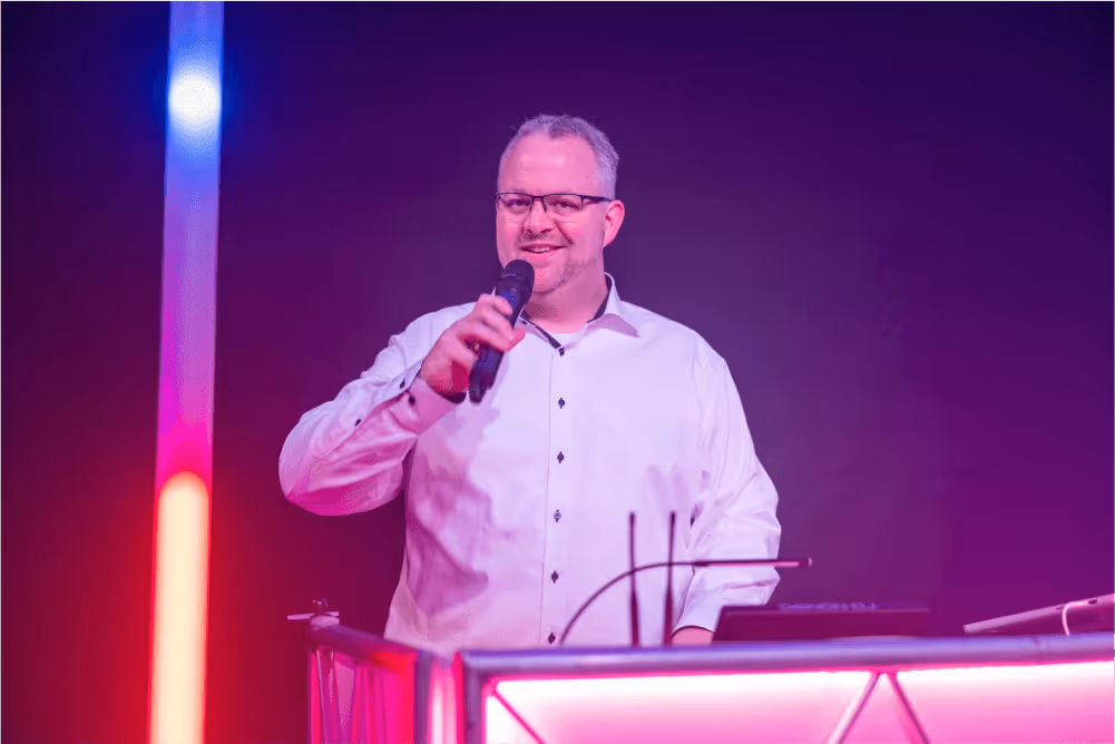 Ein Dj steht am DJ-Pult und spricht ins Mikrofon