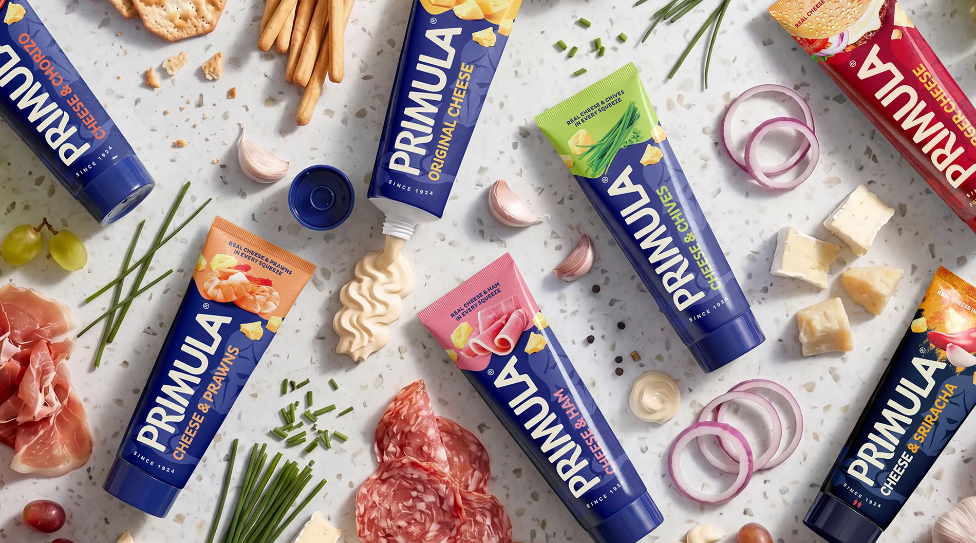 Versatile packaging design for Primula cheese spread tubes, showing the "Deli" and "Cheddar" ranges with fresh ingredient photography to highlight product usage and versatility.