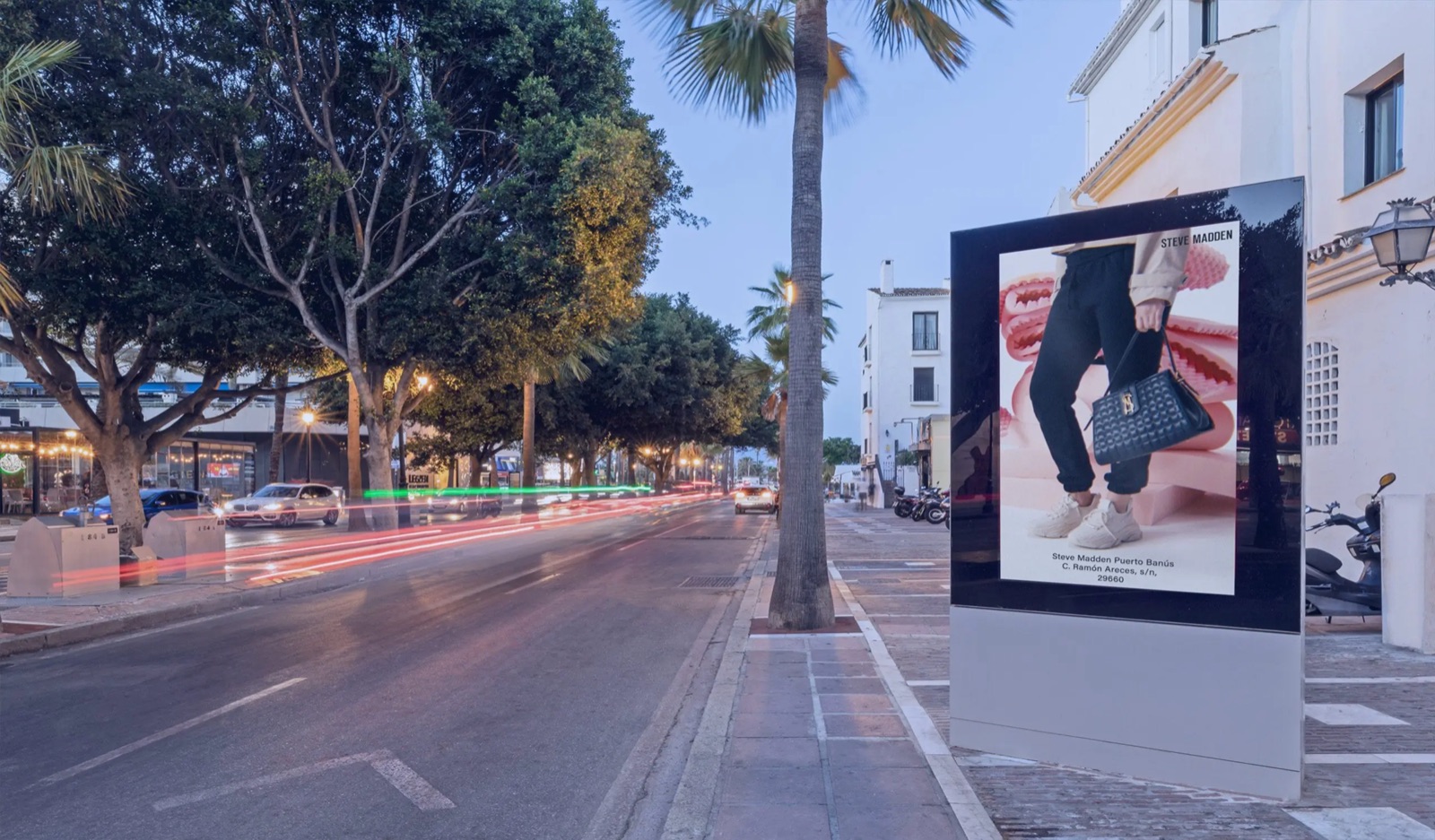 Digital advertising screen on a palm-lined street in Puerto Banus, Spain
