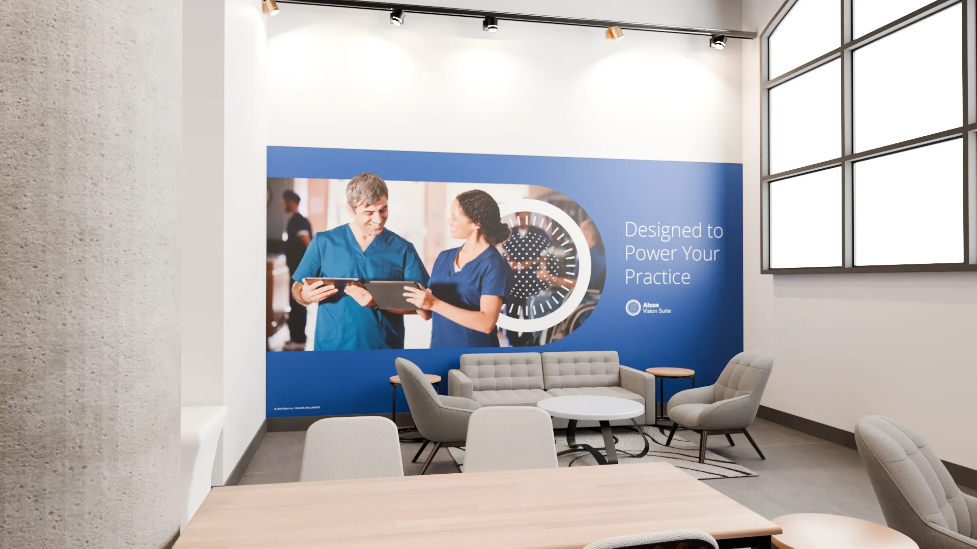 a large blue and white wall graphic with the text "Designed to Power Your Practice" and an image of two medical professionals in scrubs reviewing a tablet together. In the foreground, there is a conference table with chairs around it, and a couch and armchairs in the background. The overall impression is of a modern, technology-focused medical or healthcare workspace.