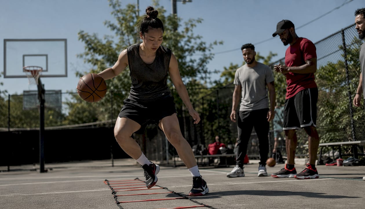 Basketball player dribbling through agility ladder indoors