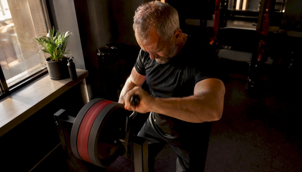 Coach using flywheel trainer in gym