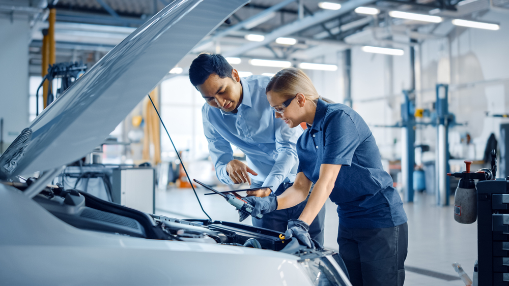 Man consulting with a mechanic about his leased car’s repair and maintenance costs.