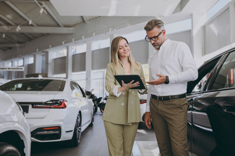 A car saleswoman reviews trade-in offer with man