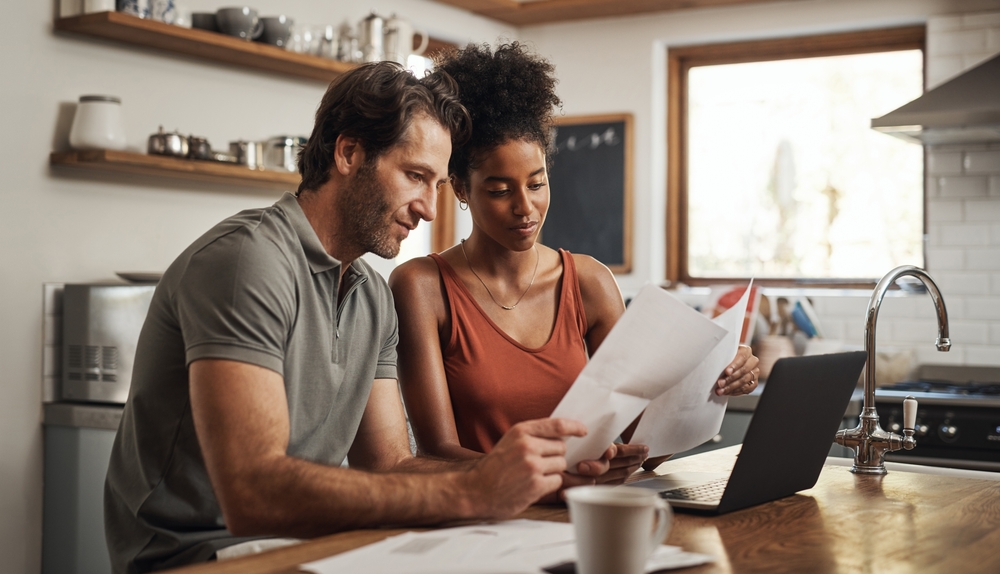 A man and a woman look over their lease paperwork while seated at the kitchen island.