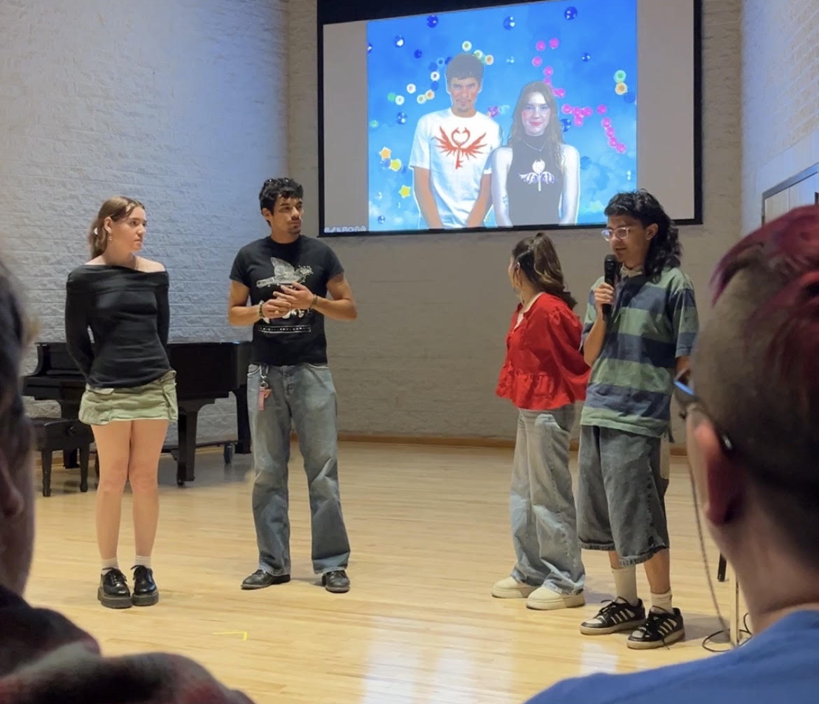 Four students explain their competition entry, displayed on the screen behind them.