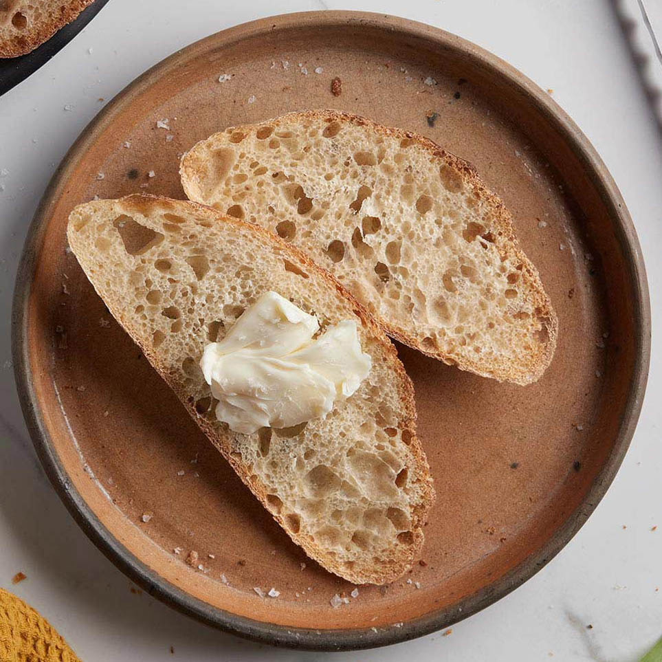 2 pieces of white sourdough bread with butter on a plate