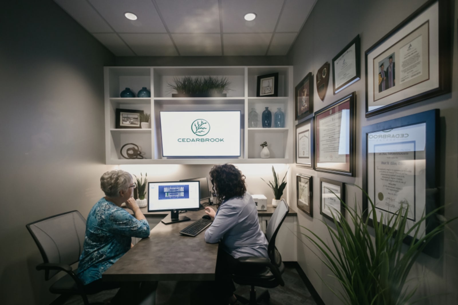 Dentist consulting with patient in clinical office, reviewing dental imaging on screen