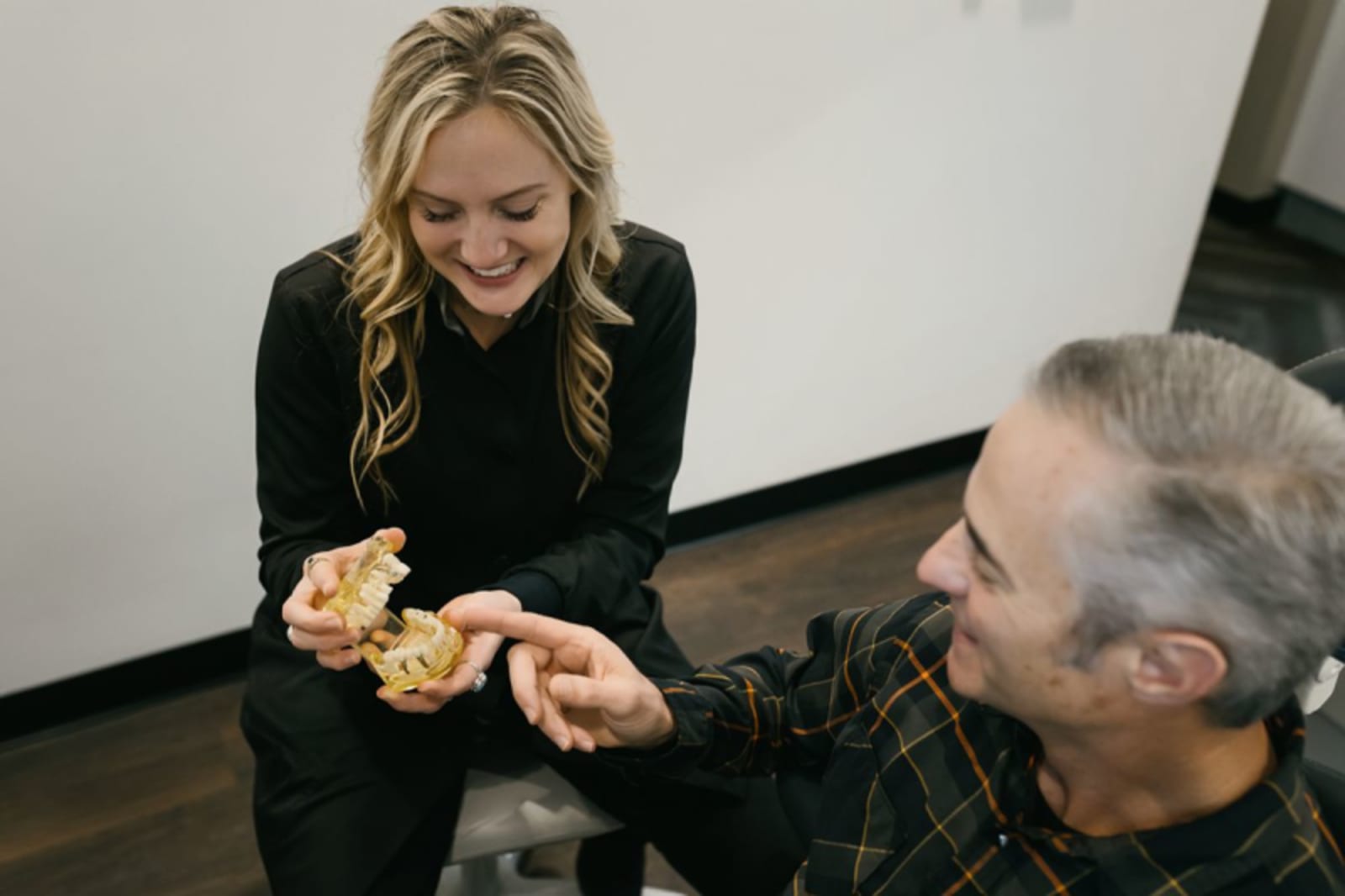 Dentist explaining dental procedure with model to senior patient