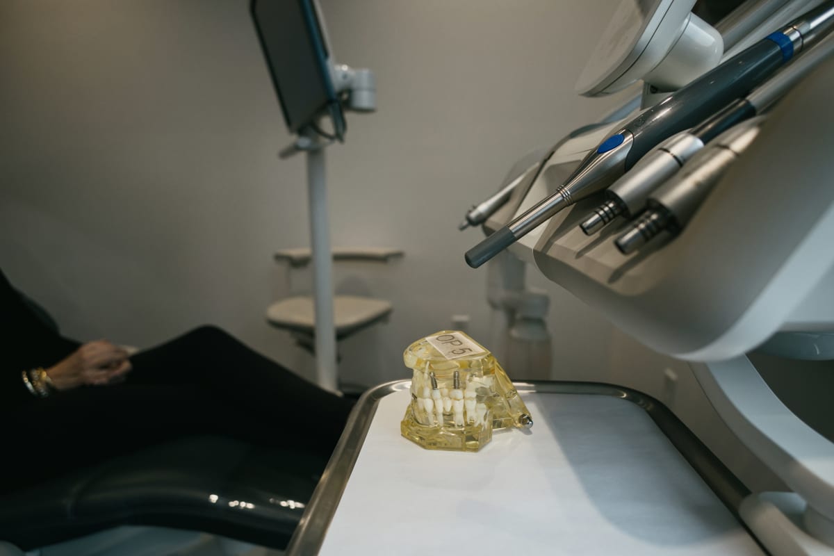 Dentist examining dental implant model under overhead light in clinical setting