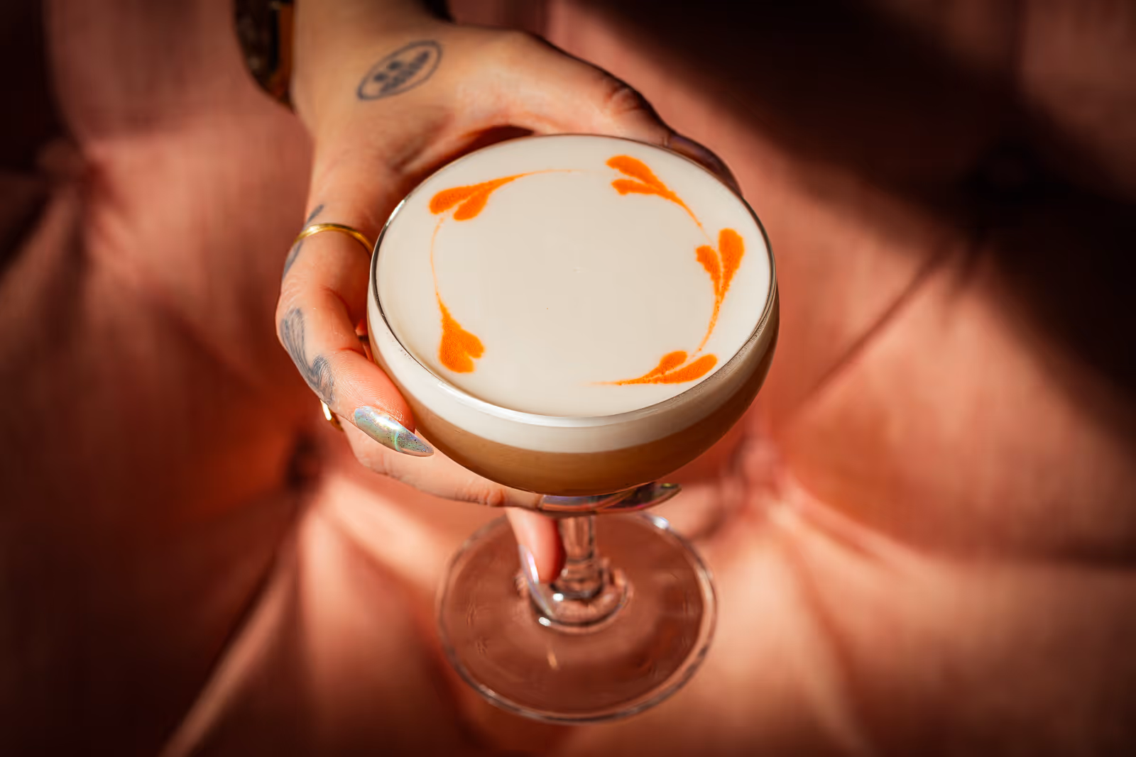 a photograph of a hand holding a beautiful cocktail from Voltaire in Kansas City