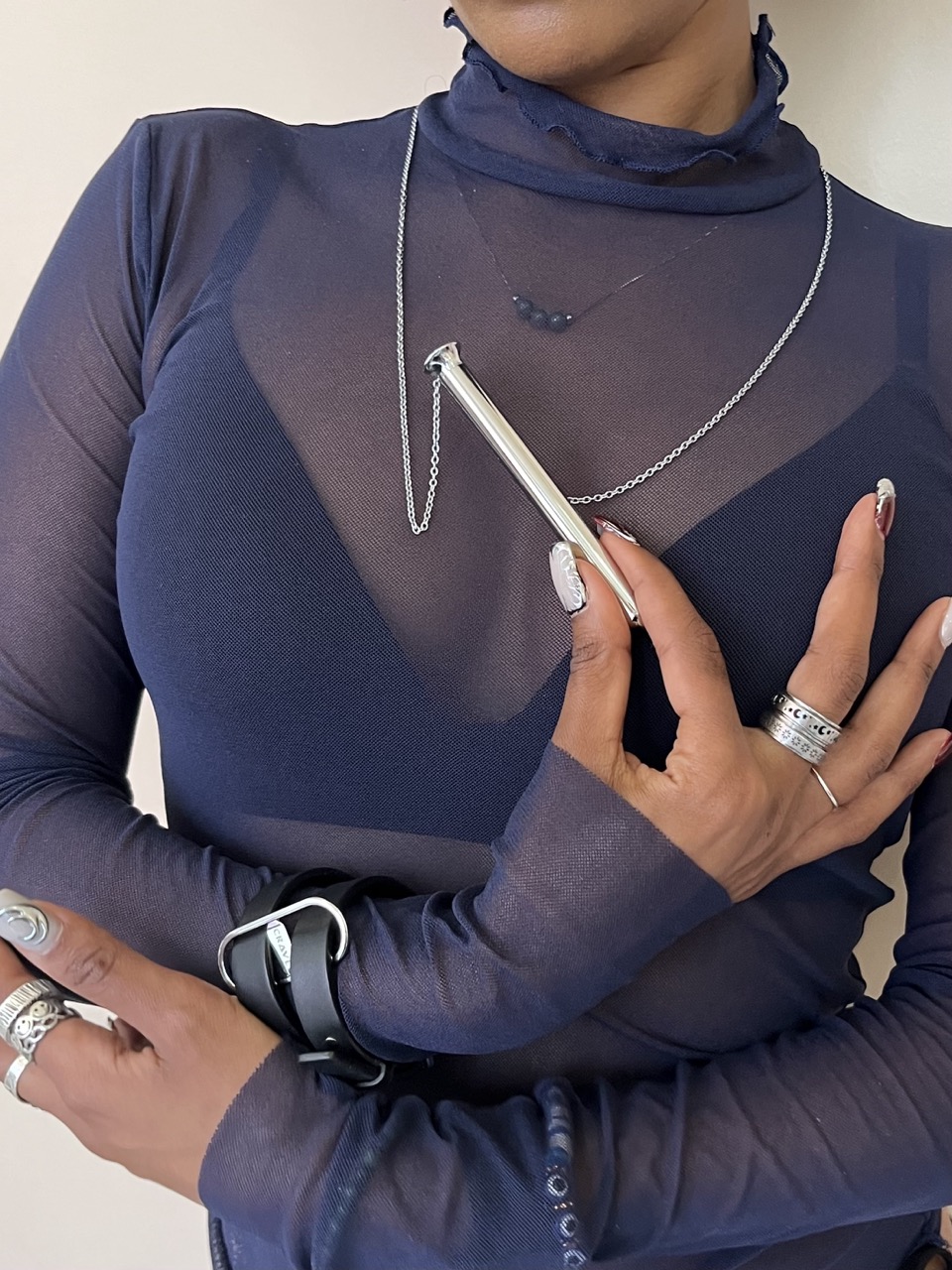 A woman in a sheer shirt holding a vibrating necklace