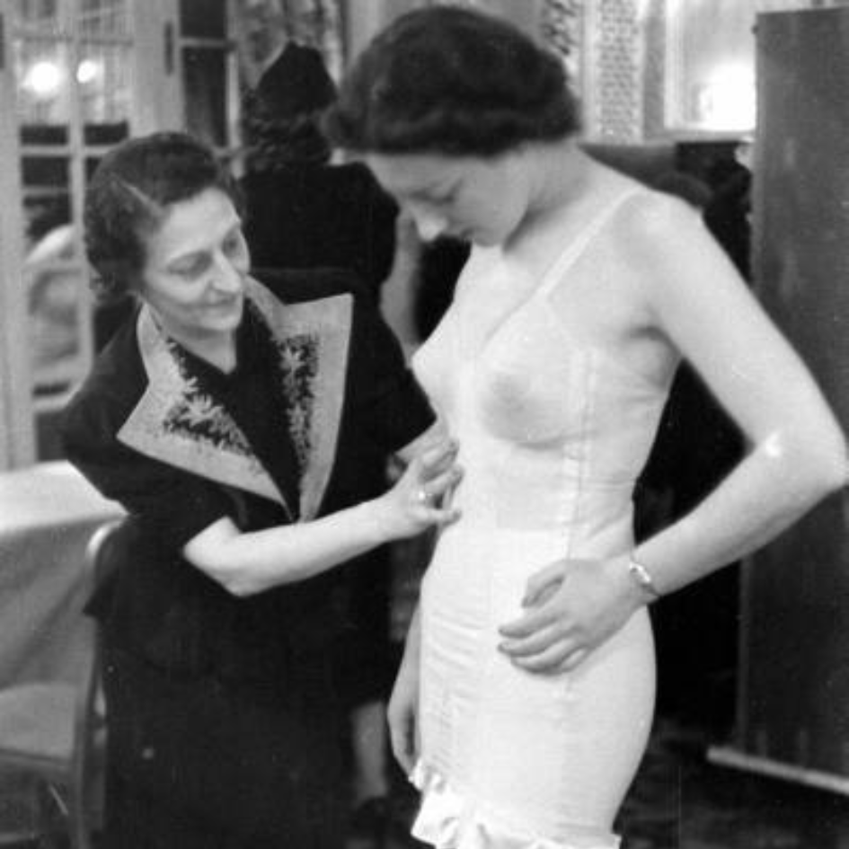 A black and white photo of a woman fitting a model