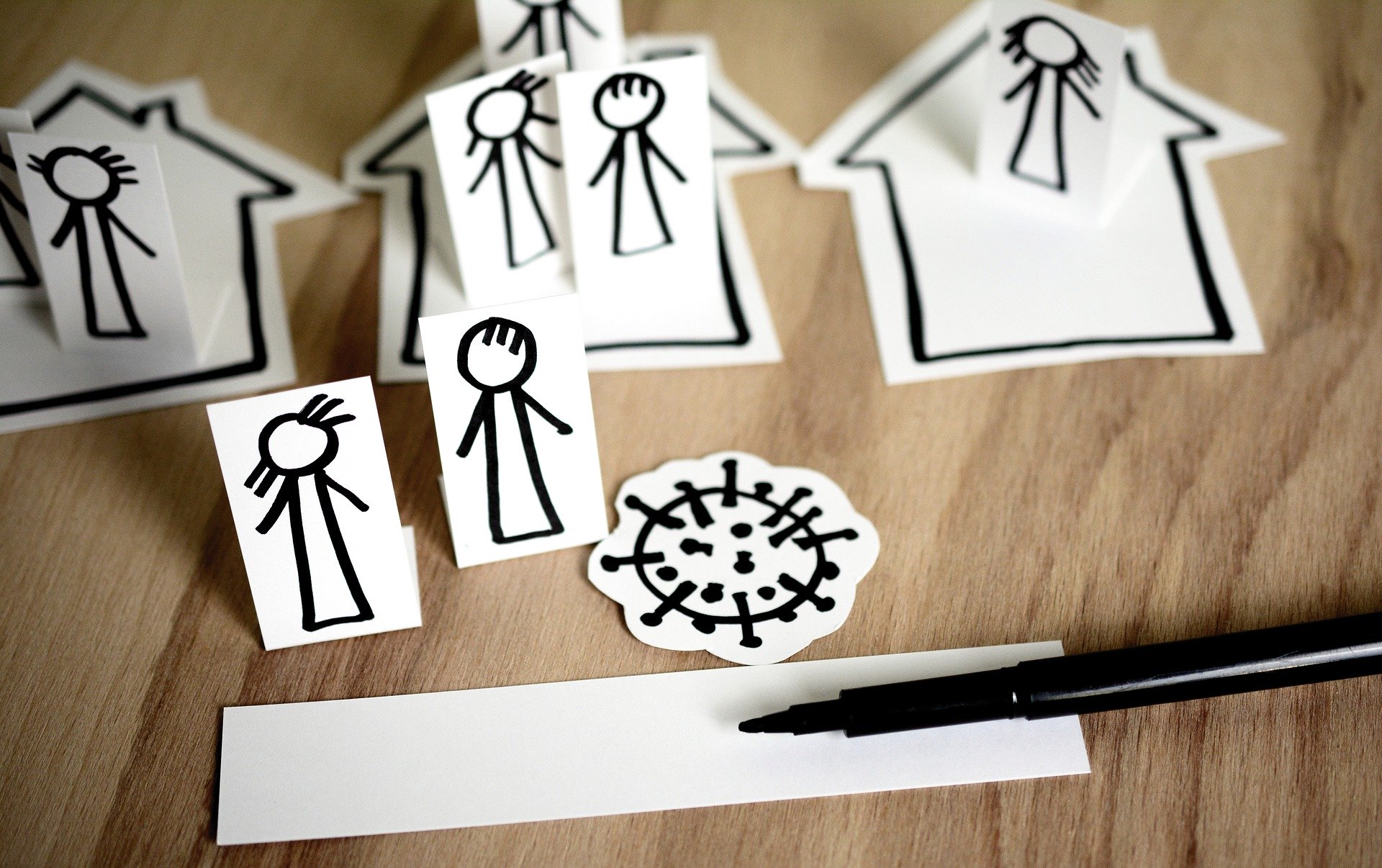 Papierfiguren mit Coronavirus auf Küchentisch