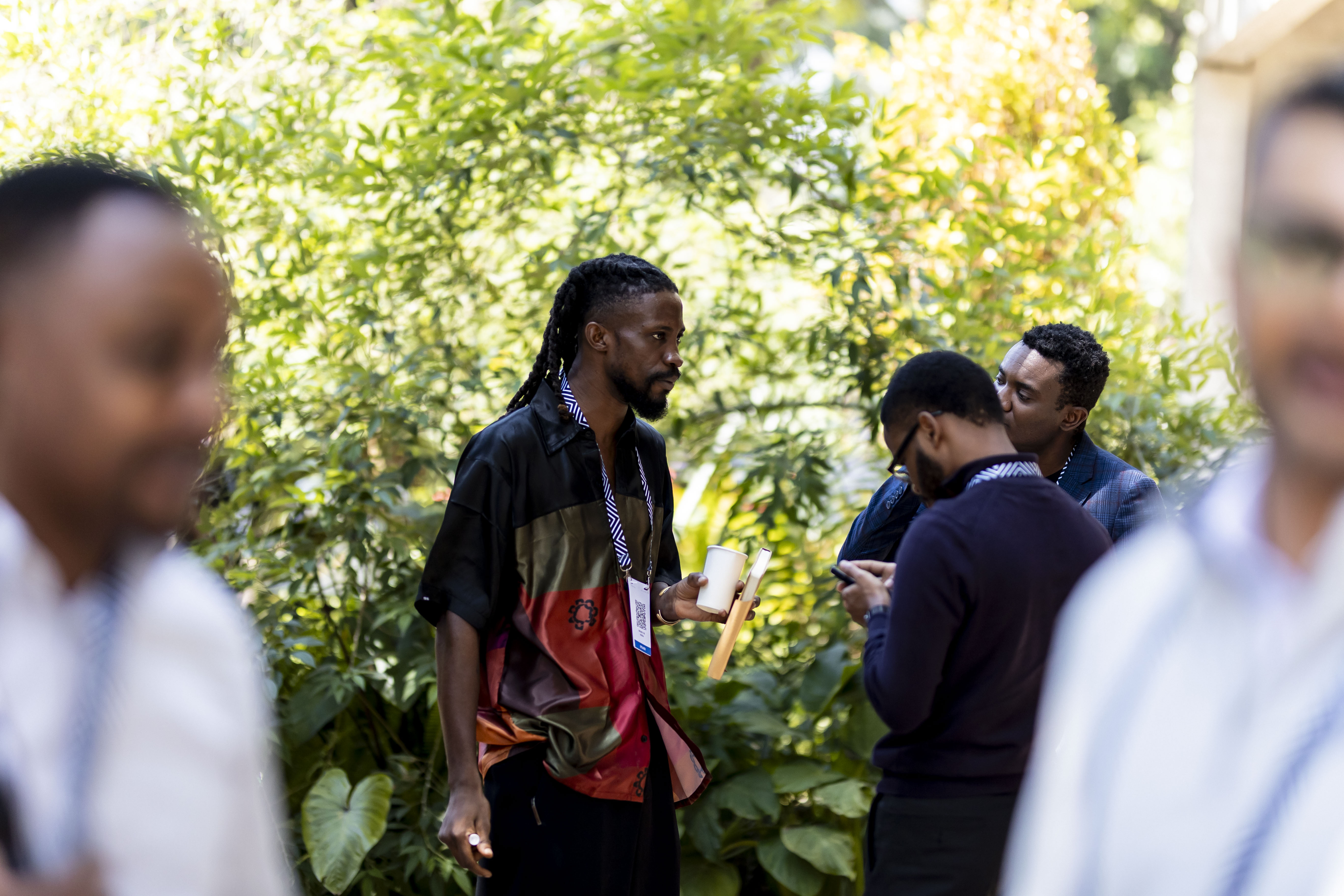 Four young adults sitting and smiling on bean bags outdoors with large white letters in the background during Africa/Week 2025