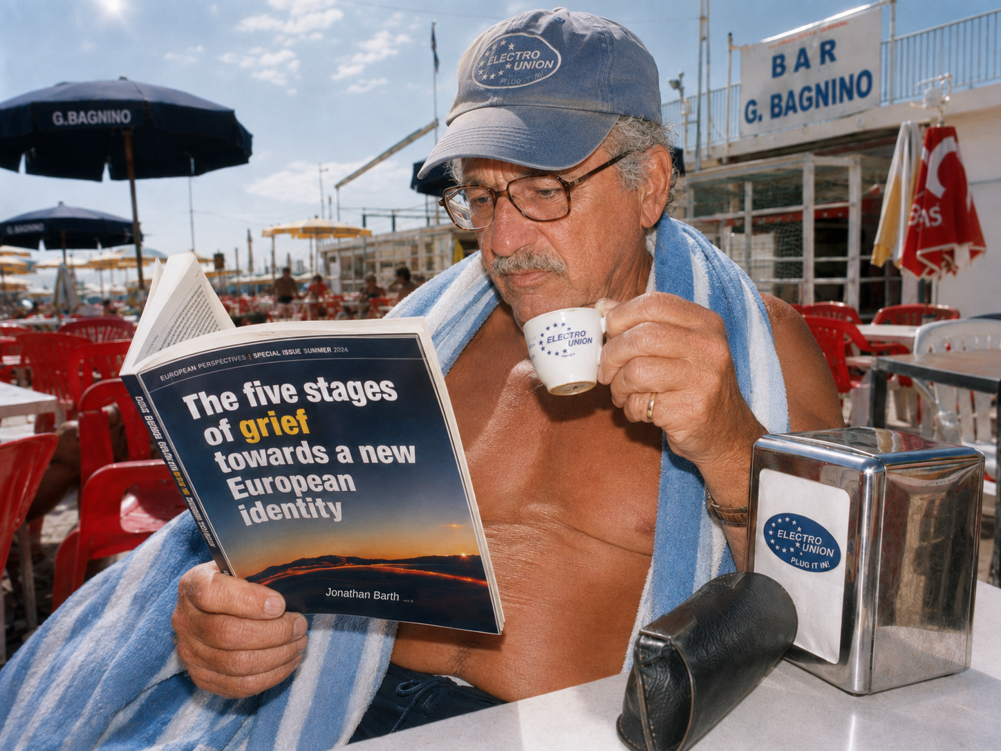 Man reading a mock magazine titled 'The five stages of grief towards a new European identity' at a beach bar, wearing an 'Electro Union' cap