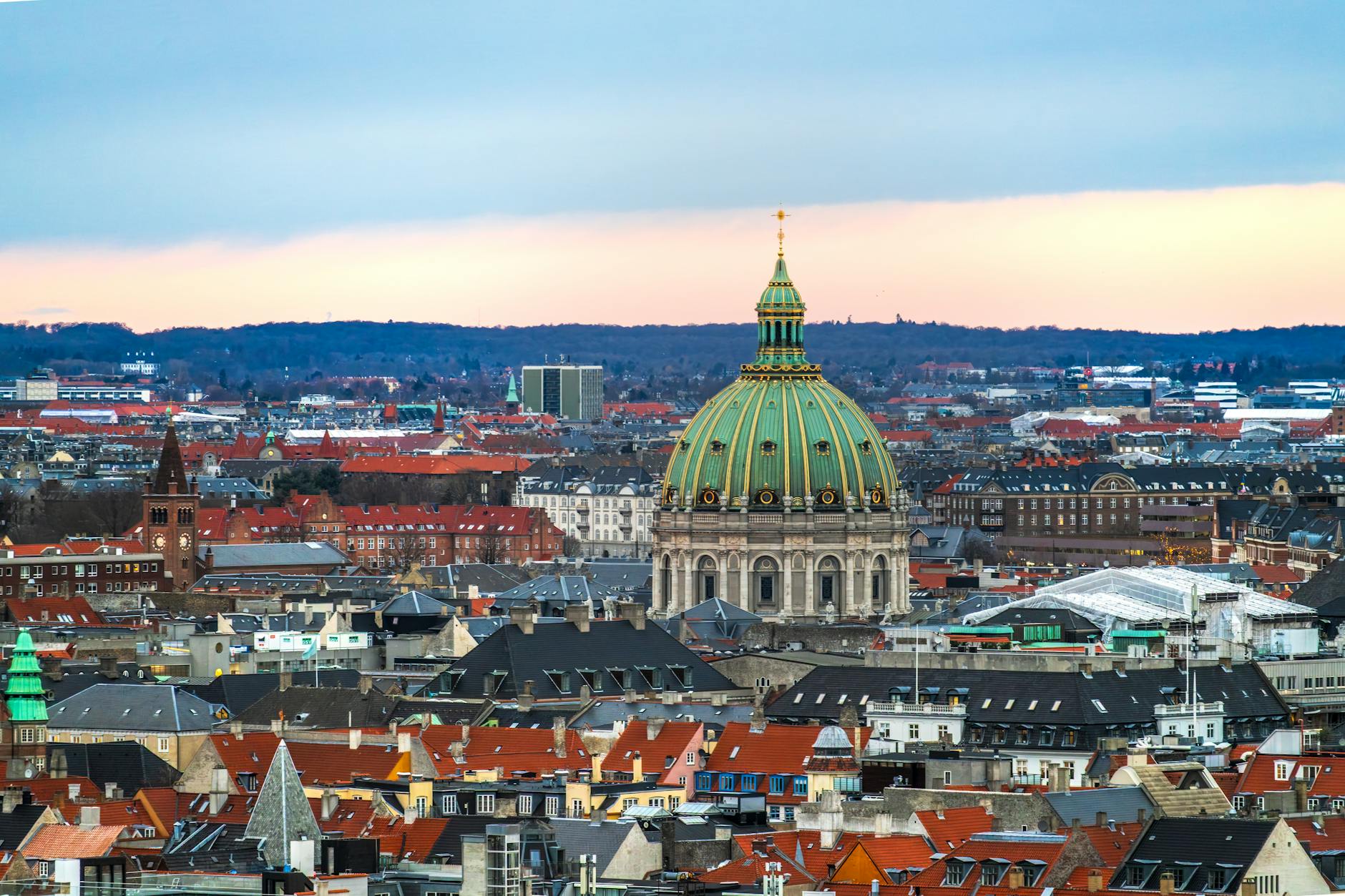 Stunning aerial view of Frederik's Church and Copenhagen skyline at sunset with iconic architecture.