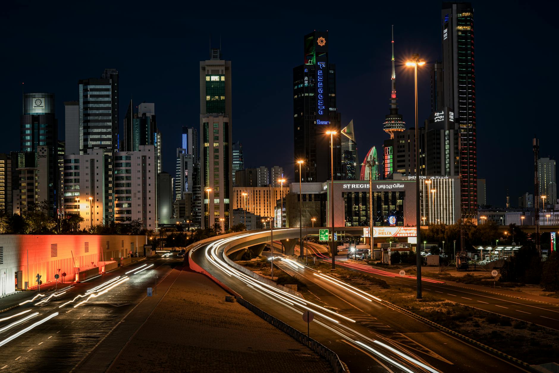 Vibrant night view of Kuwait City's skyline showcasing modern architecture and light trails.