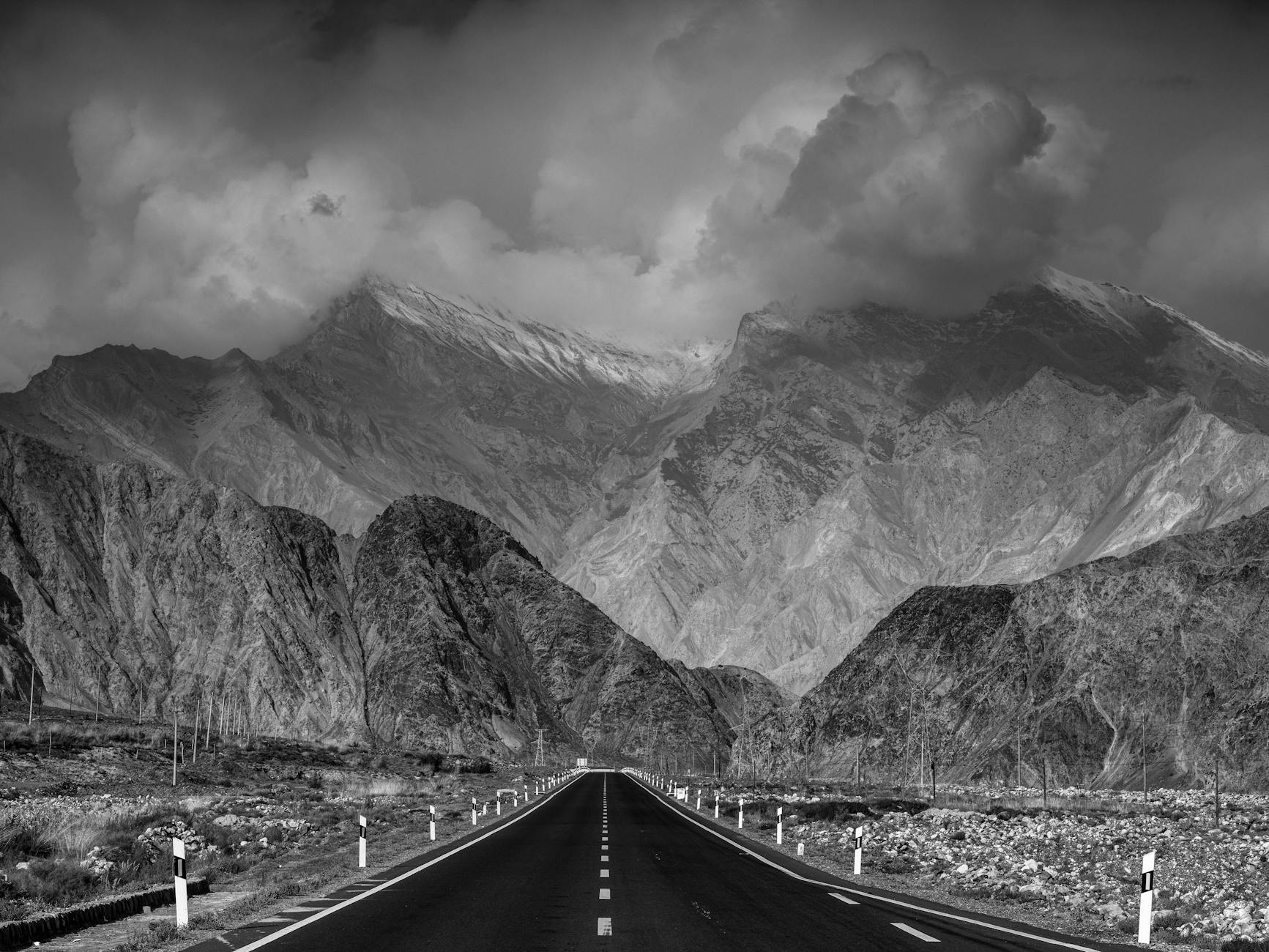 Majestic mountains with a scenic road, captured in dramatic grayscale.