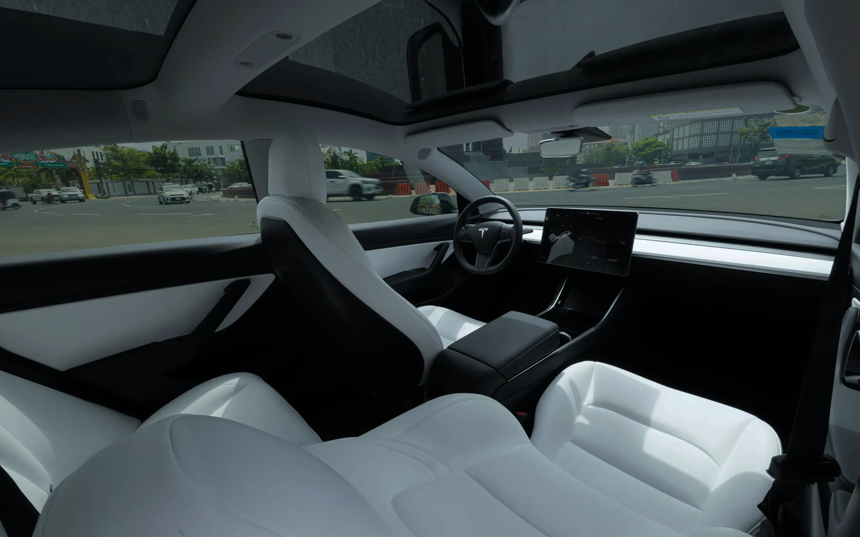 Interior of car with white leather seat, steering wheel, and dashboard.