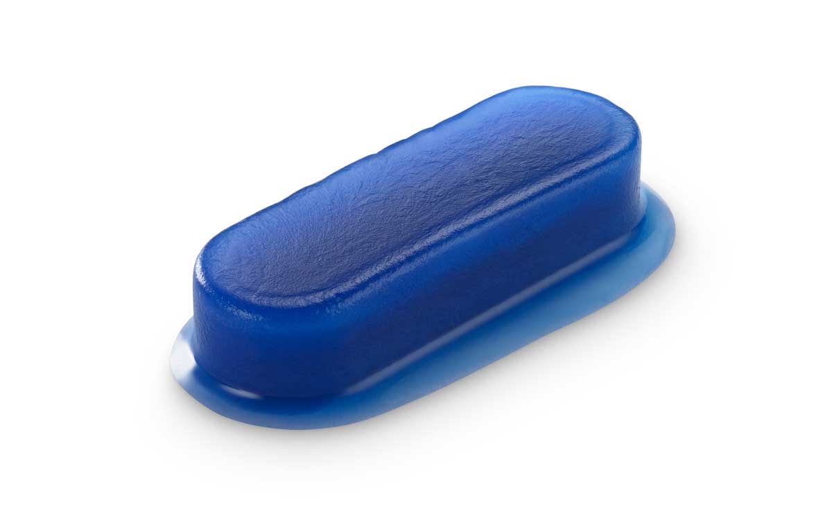 Close-up of a hemostatic dressing on a white surface with water droplets scattered around.