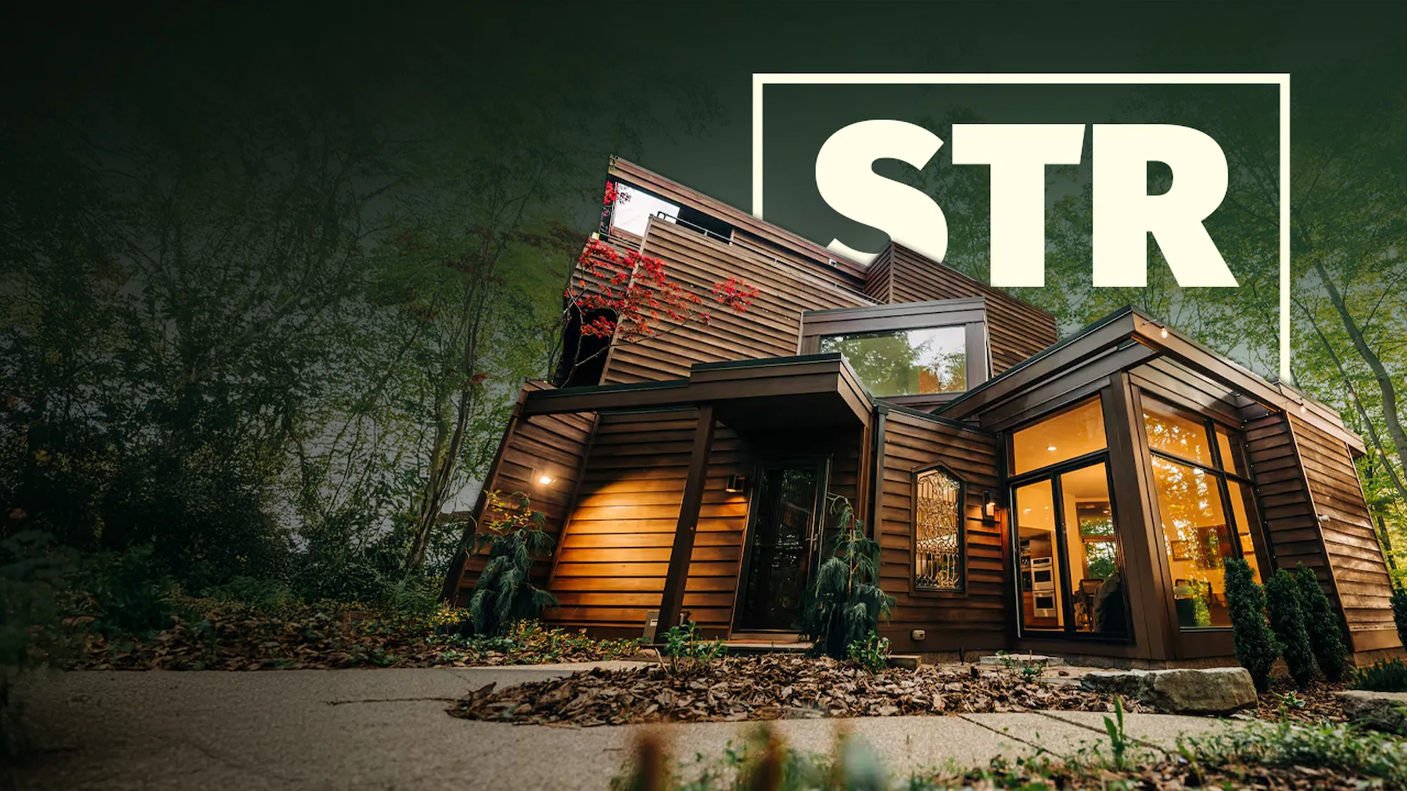 Modern tiny house with wood siding and warm interior lights surrounded by trees at dusk