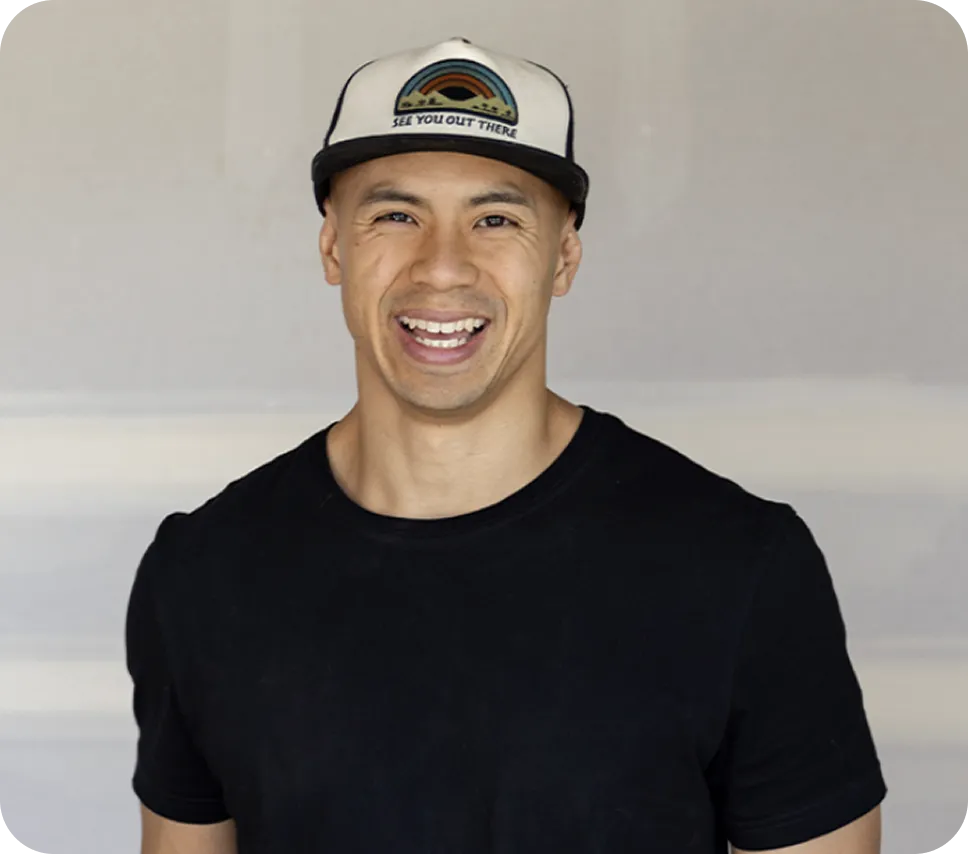 Man smiling wearing white and black baseball cap with rainbow design