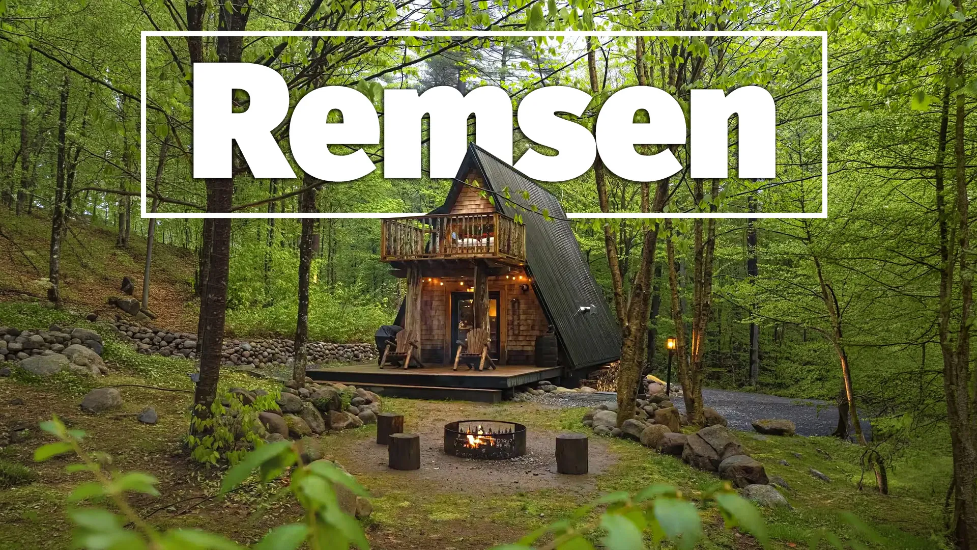 Modern A-frame cabin in forest with firepit, surrounded by green trees and nature