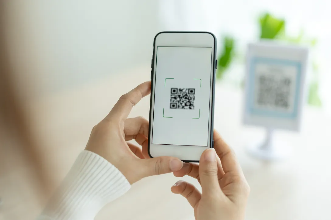 Hand holding smartphone scanning QR code with camera app open