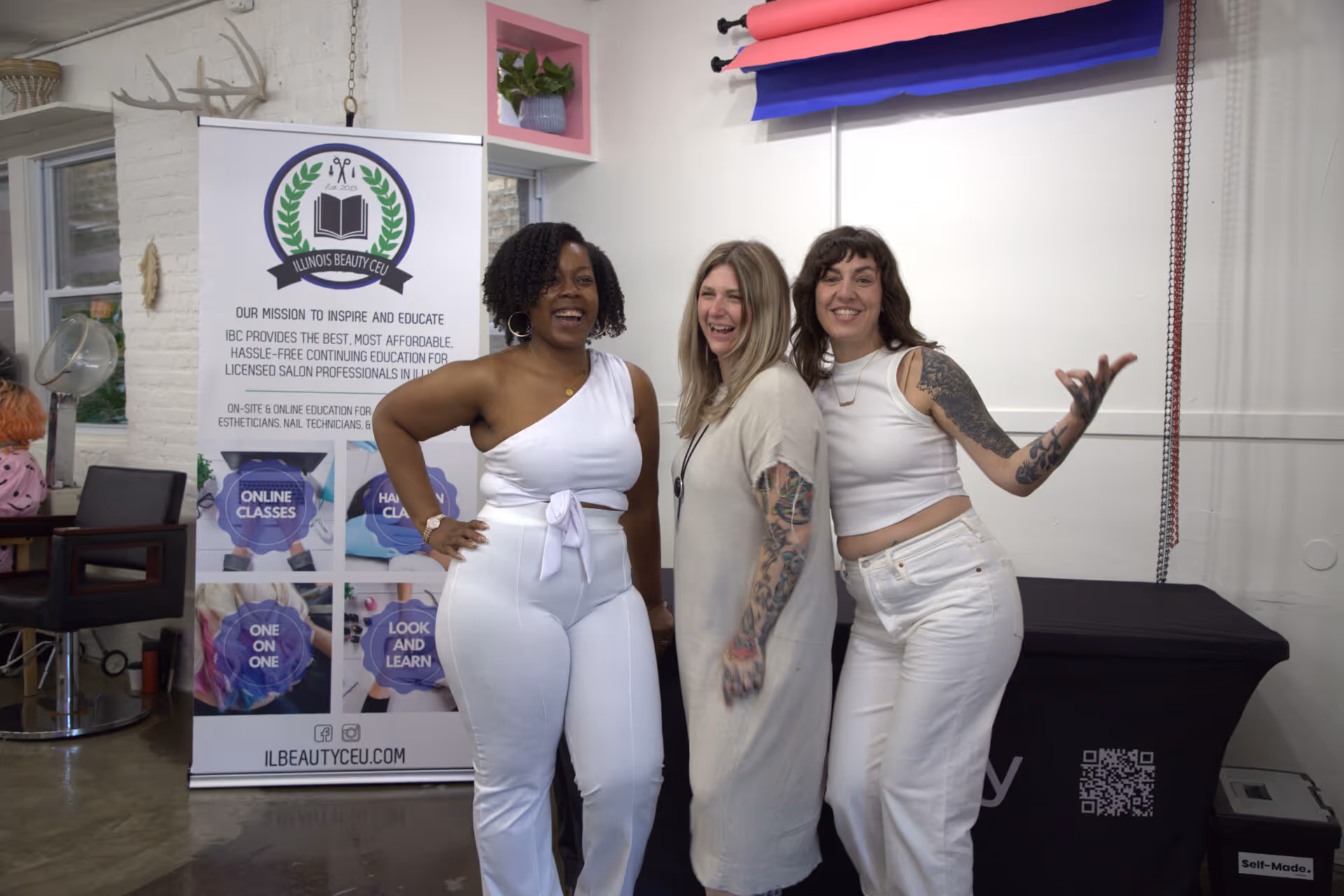 Three women smiling and posing together indoors at an Illinois Beauty CEU event.