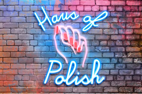 Neon sign on brick wall showing a hand with red nails and text 'Haus of Polish.'