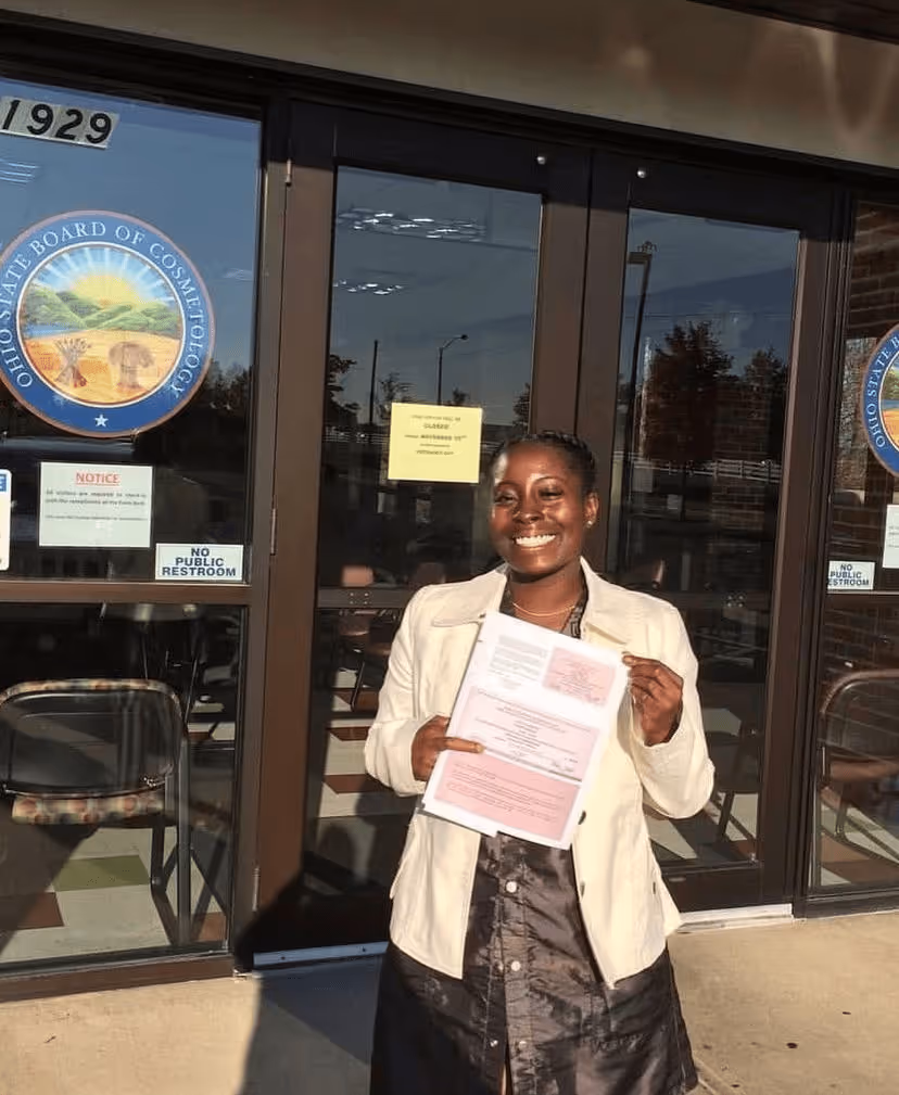 Smiling woman holding document outside Ohio State Board of Cosmetology building.
