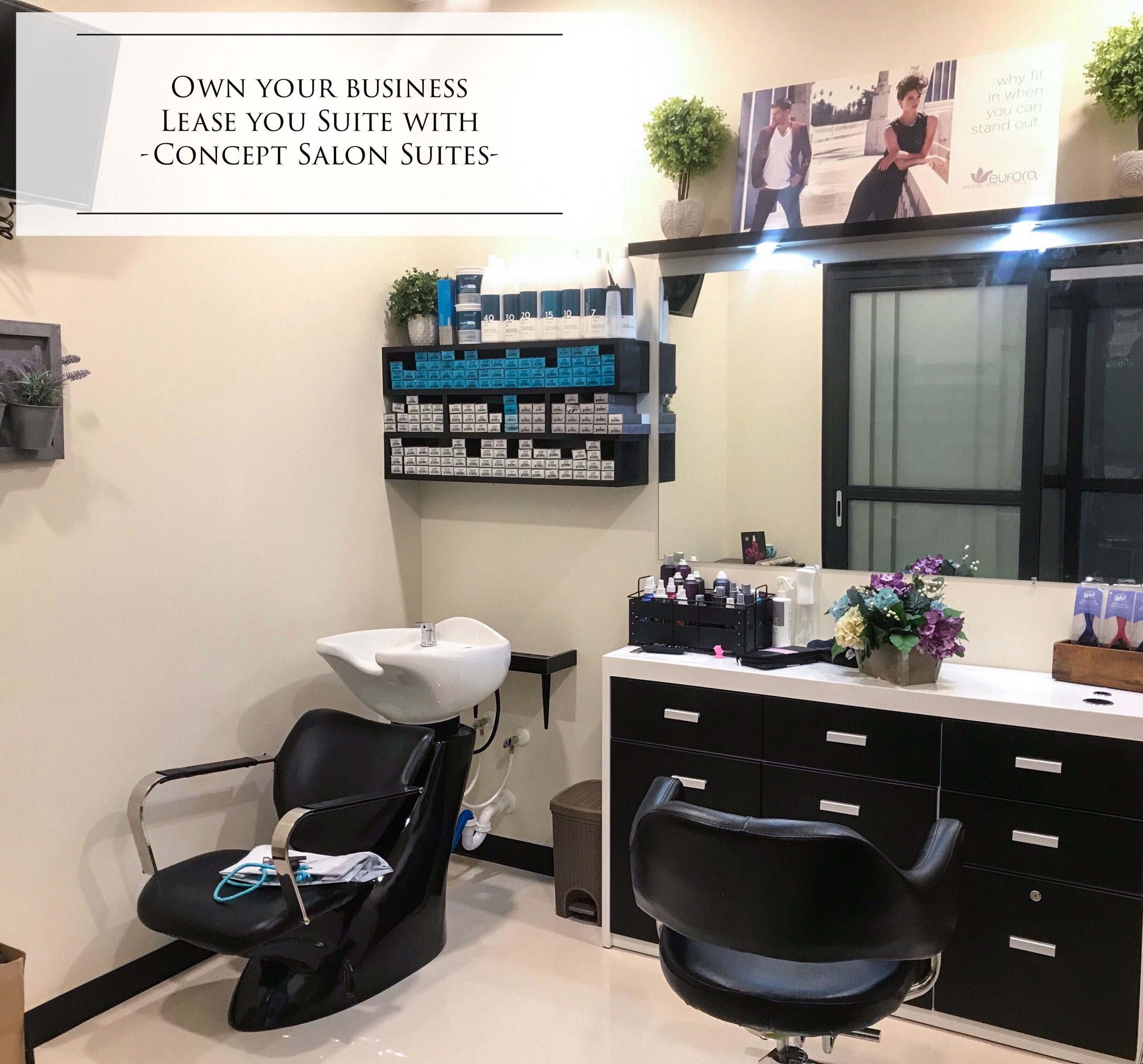 Salon suite with black styling and washing chairs, hair products shelves, flowers, and a large mirror.