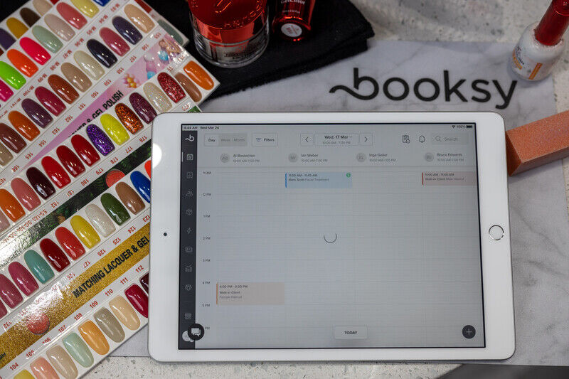 Tablet showing a calendar app with nail polish color samples and manicure tools nearby.