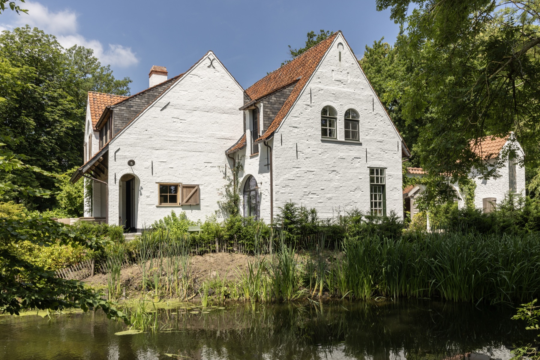 Het landhuis weerspiegeld in de vijver met rietkraag