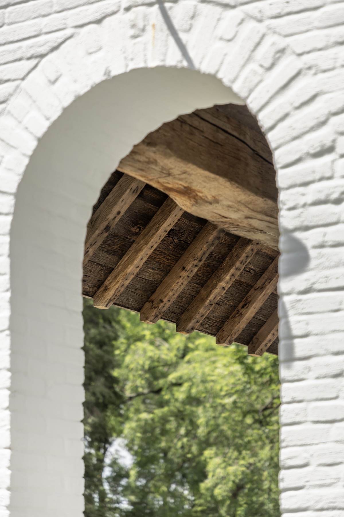 Detail van een witte boog met gerecupereerde eiken balken