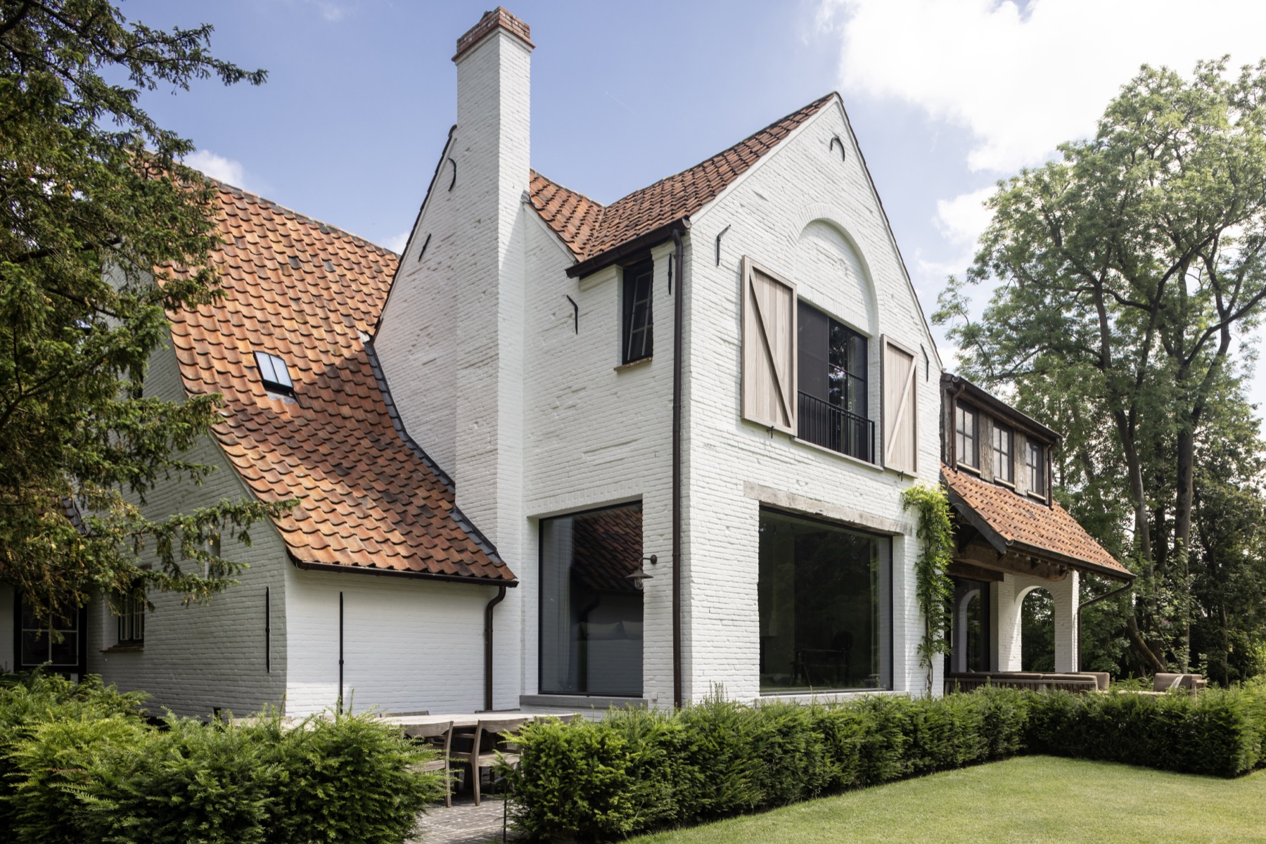 Landhuis met witte gevel en grote raampartijen gezien vanuit de tuin