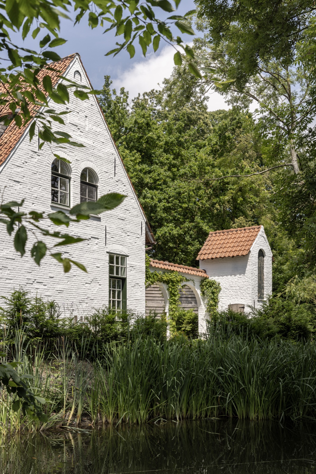 Witte tuitgevel van het landhuis door het gebladerte