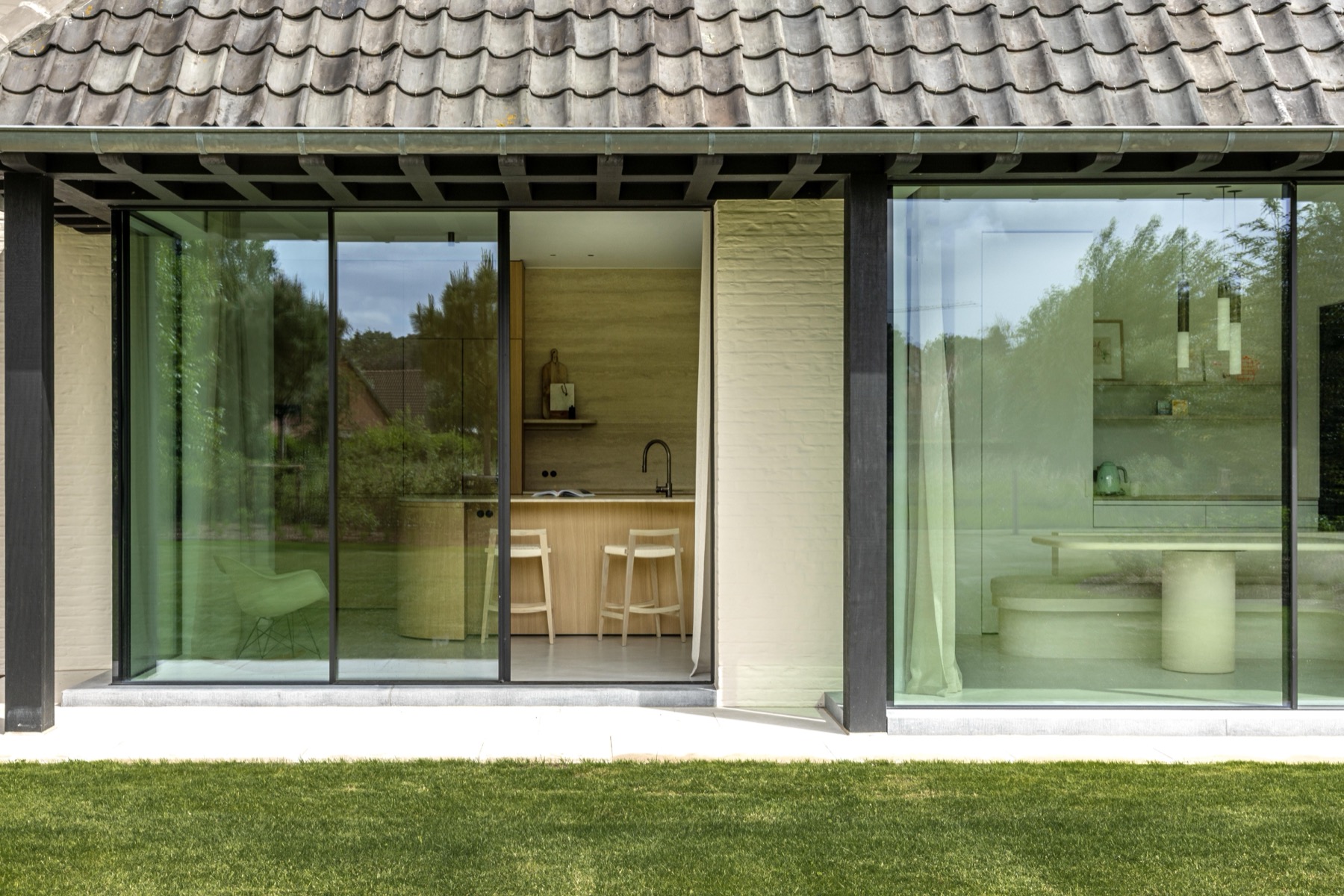 Glazen uitbouw met blauw gesmoorde pannen en zicht op de tuin