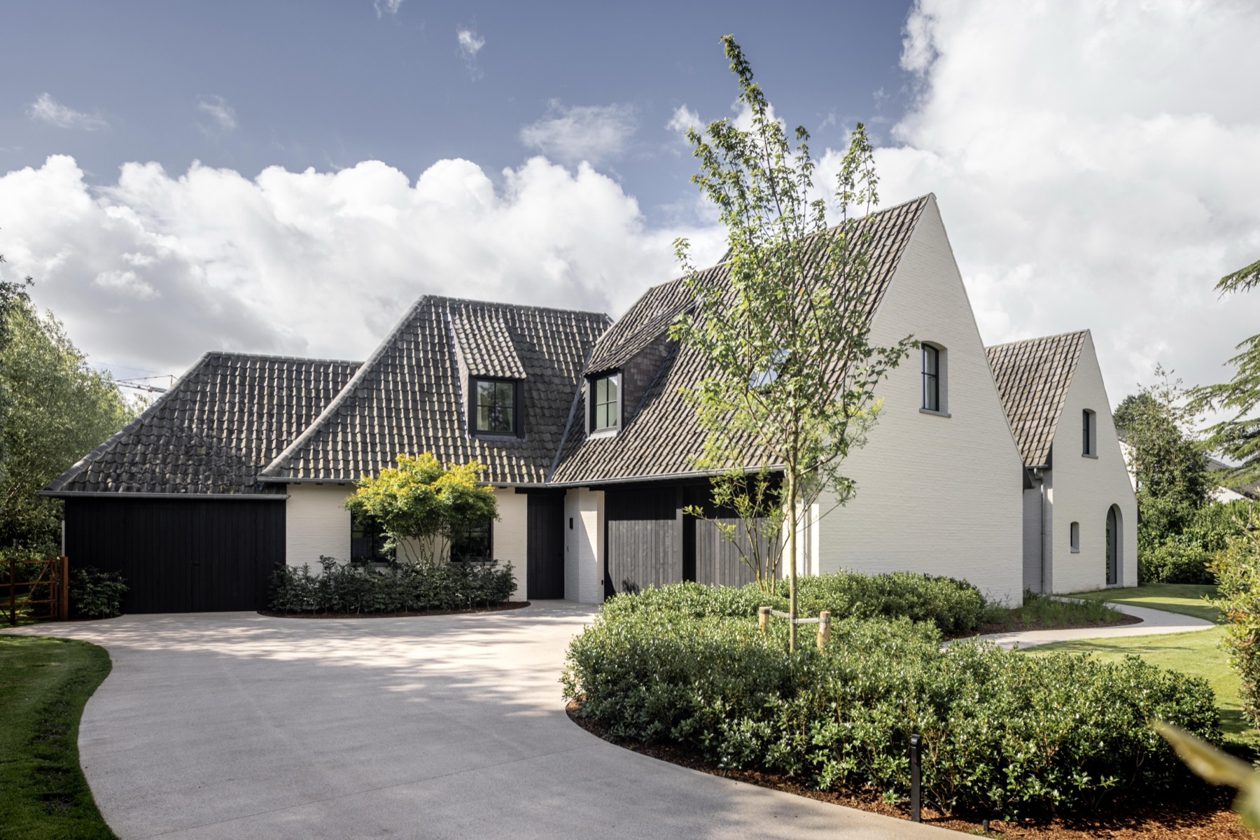 Vooraanzicht van de woning met oprit en aangelegde tuin