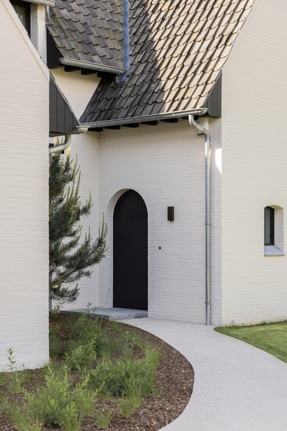 Inkom met zwarte boogdeur in de witte gevel
