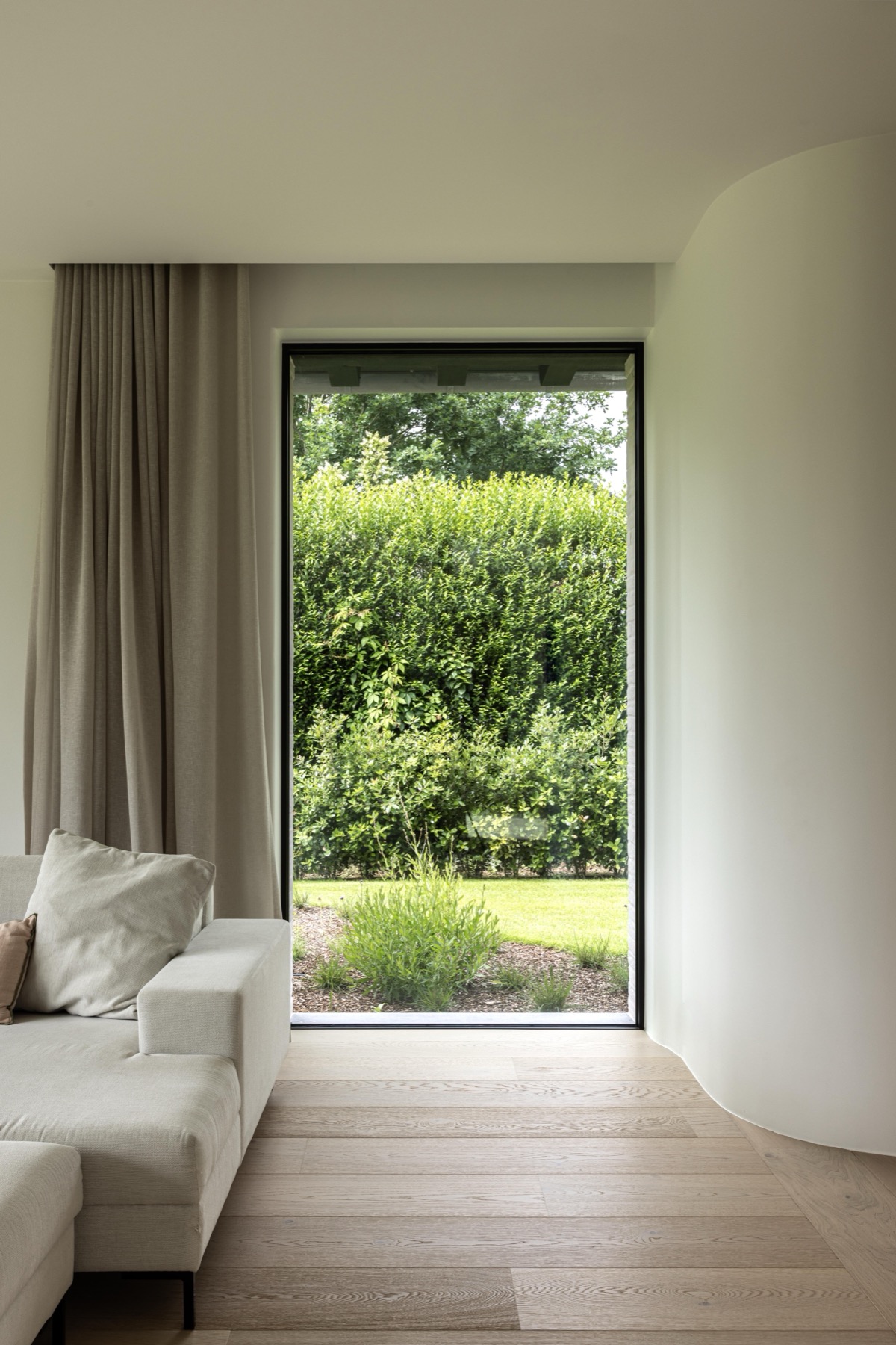 Zithoek met zetel en groot raam naar de tuin