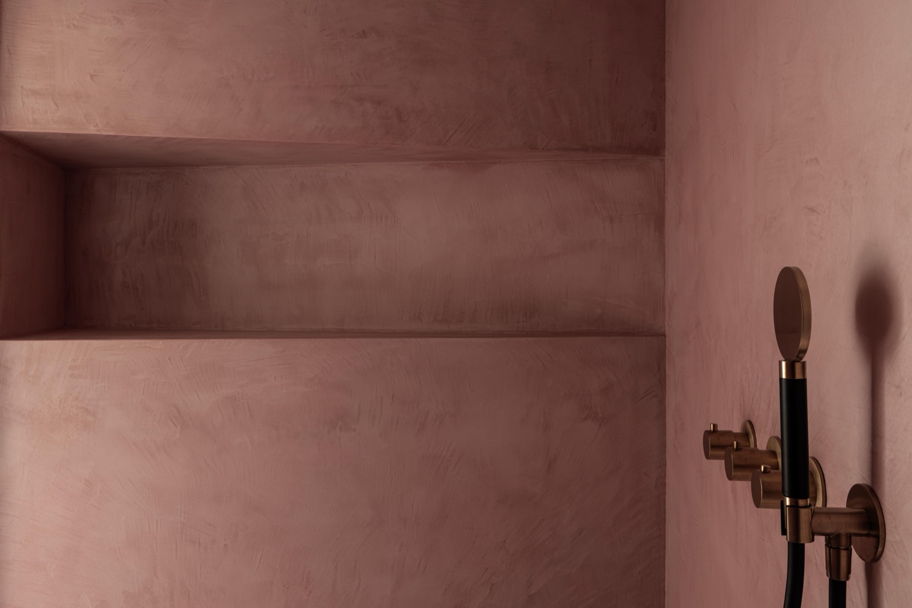 Badkamer met wand in roze Mortex en regendouche