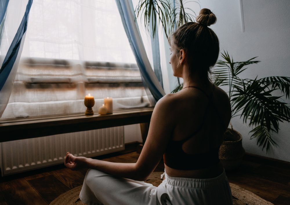 In a calming yoga pose, a blind woman sits gracefully, accompanied by a candle that adds a soothing touch to the ambiance.