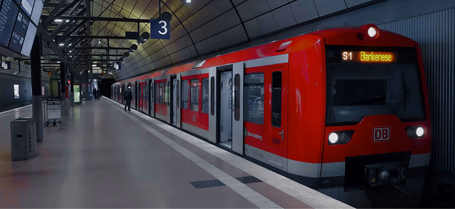 Ein roter Zug der Deutschen Bahn steht mit geöffneter Tür am Bahnsteig 3 eines modernen Bahnhofs, Anzeige zeigt S1 Richtung Borkenese.