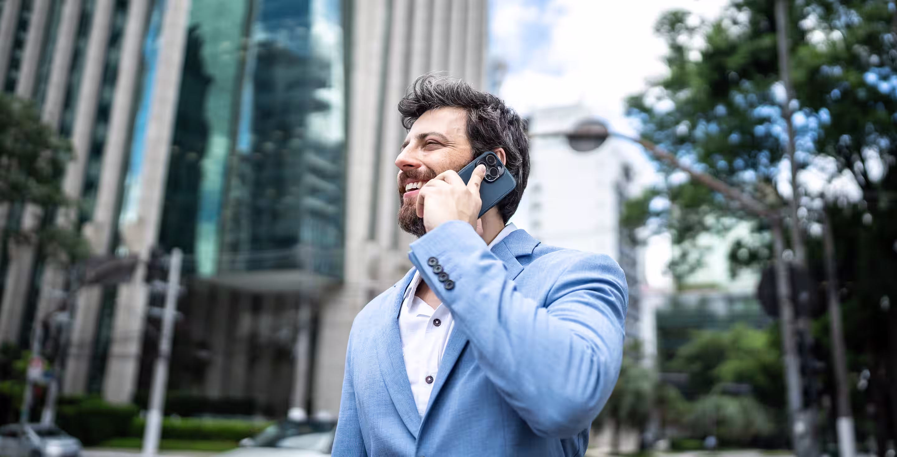 Lächender Mann telefoniert in Großstadt.
