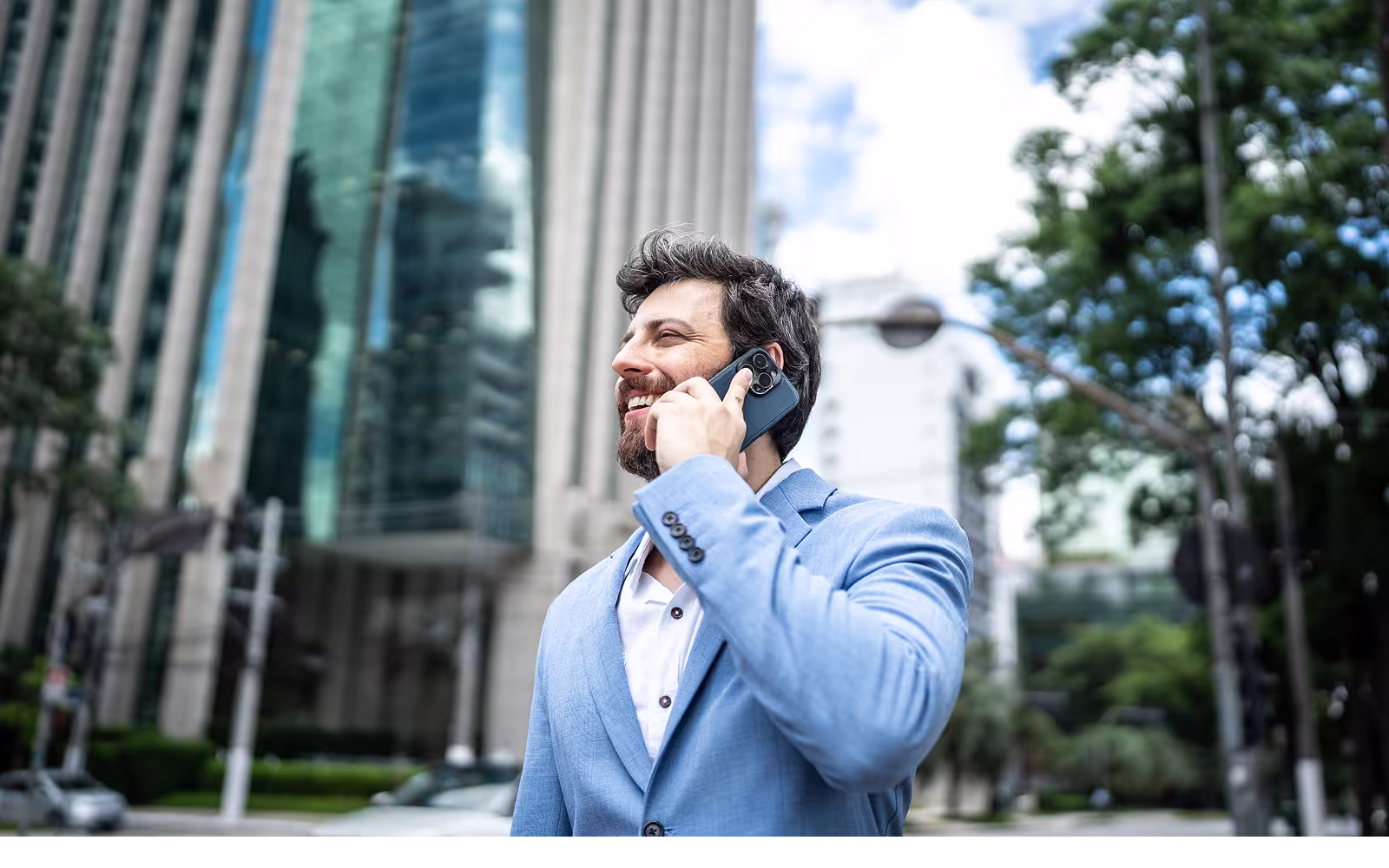 Lächender Mann telefoniert in Großstadt.